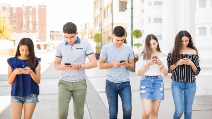 a group of teens walking while using their phones