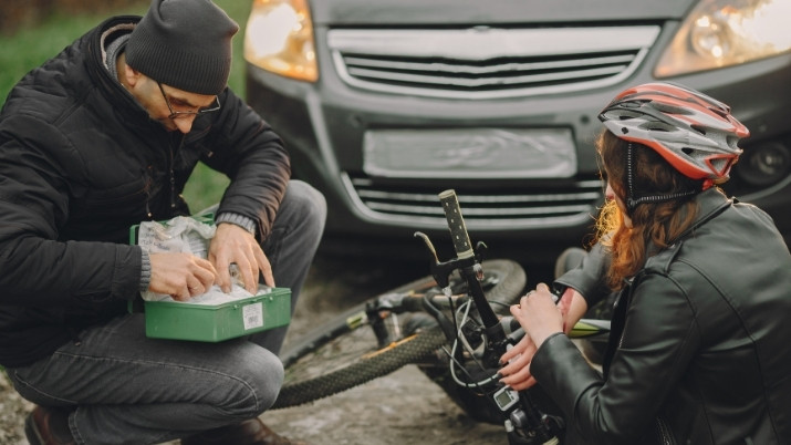 man giving a frist aid care to a biker after an accident