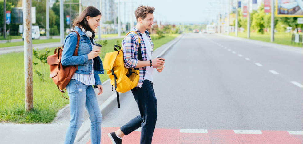 two pedestrian walking while holding coffee