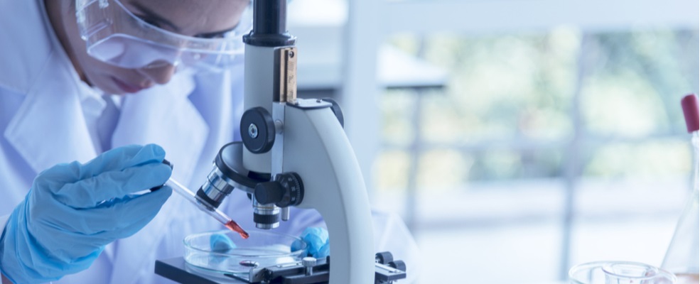 woman studying virus in a microscope