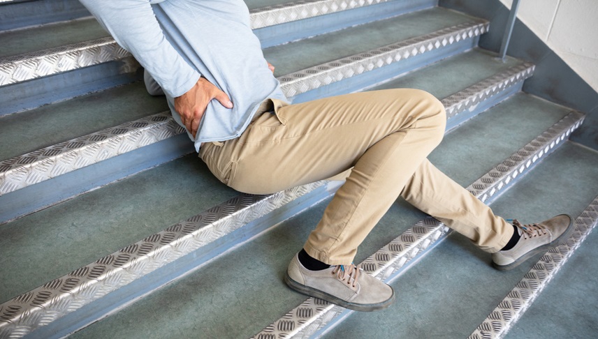 man touching his back after falling from stairs