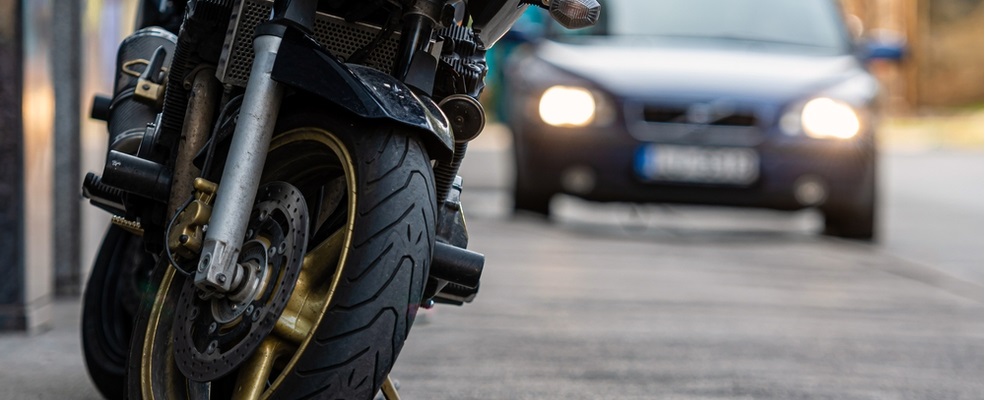 motorcycle park in sidewalk while a car is approaching