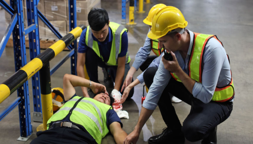 safety officer team helping warehouse worker who had head injury