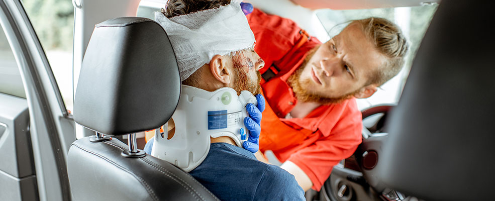 emergency personnal treating a man after a car crash