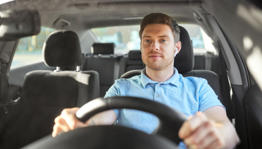 man using one wireless earphones while driving