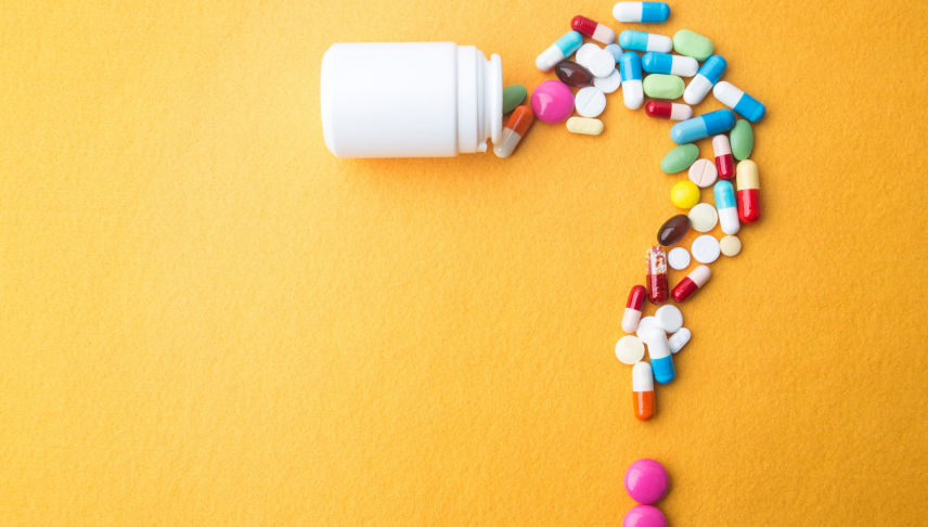 pills and capsules as a question mark and white plastic bottle