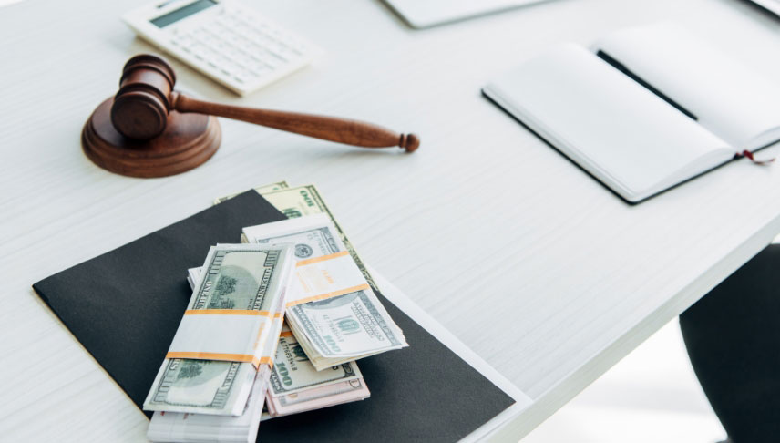 gavel notebook calculator and dollar bills on white table