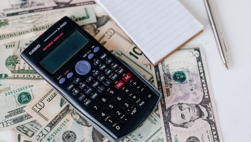calculator notepad pen and different dollar bills