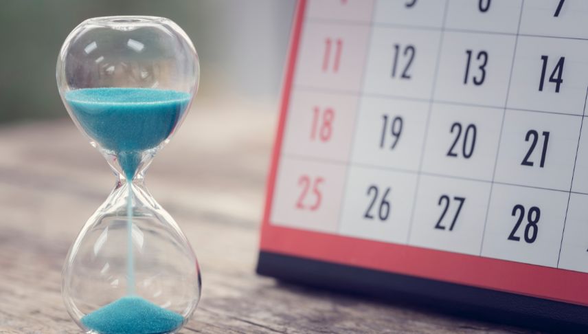 hour glass and calendar on wooden table