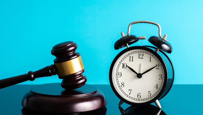 black alarm clock and gavel on blue background