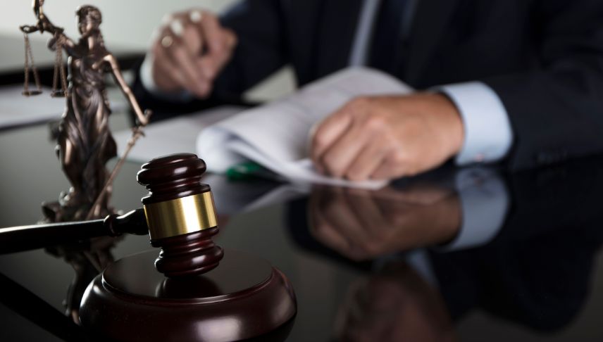 lawyer writing at a table with a gavel and scales of justice