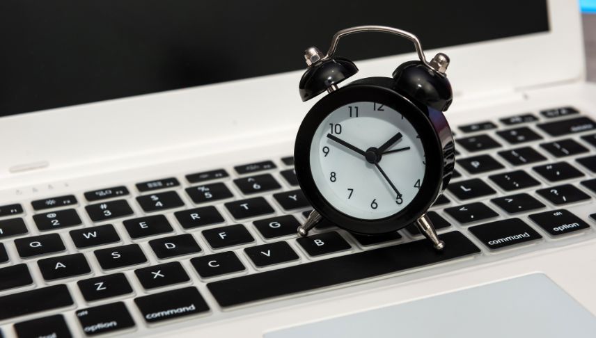 laptop with alarm clock on top of keyboard