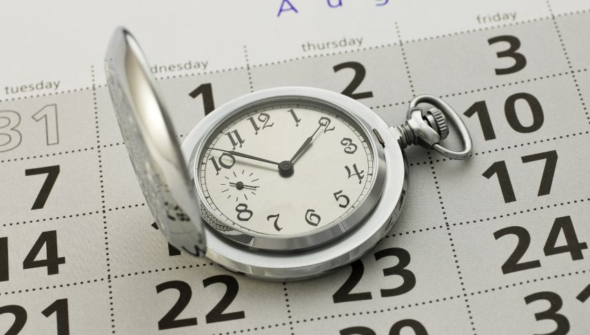 silver pocket clock on black and grey calendar