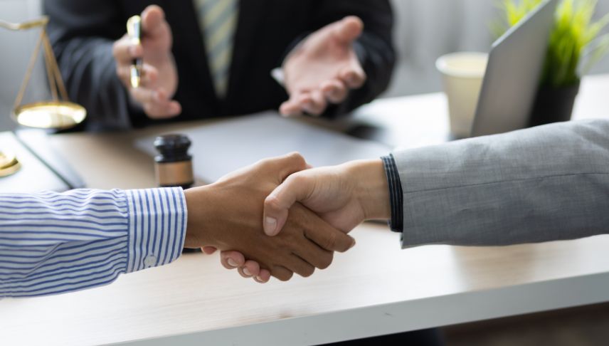 clients shake hands after settlement agreement with attorney