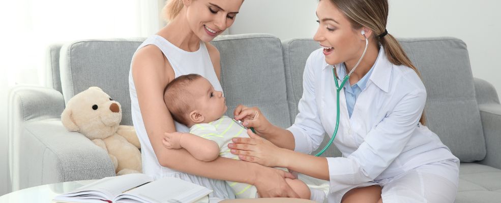 doctor examining baby with stethoscope at home