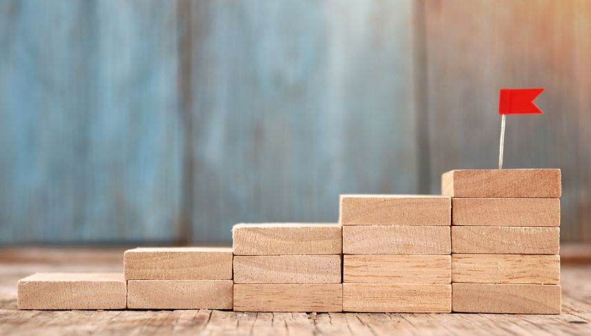 increasing stack of wooden blocks with red flag on top