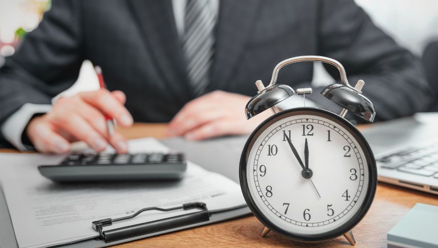 man using calculator with clock in front