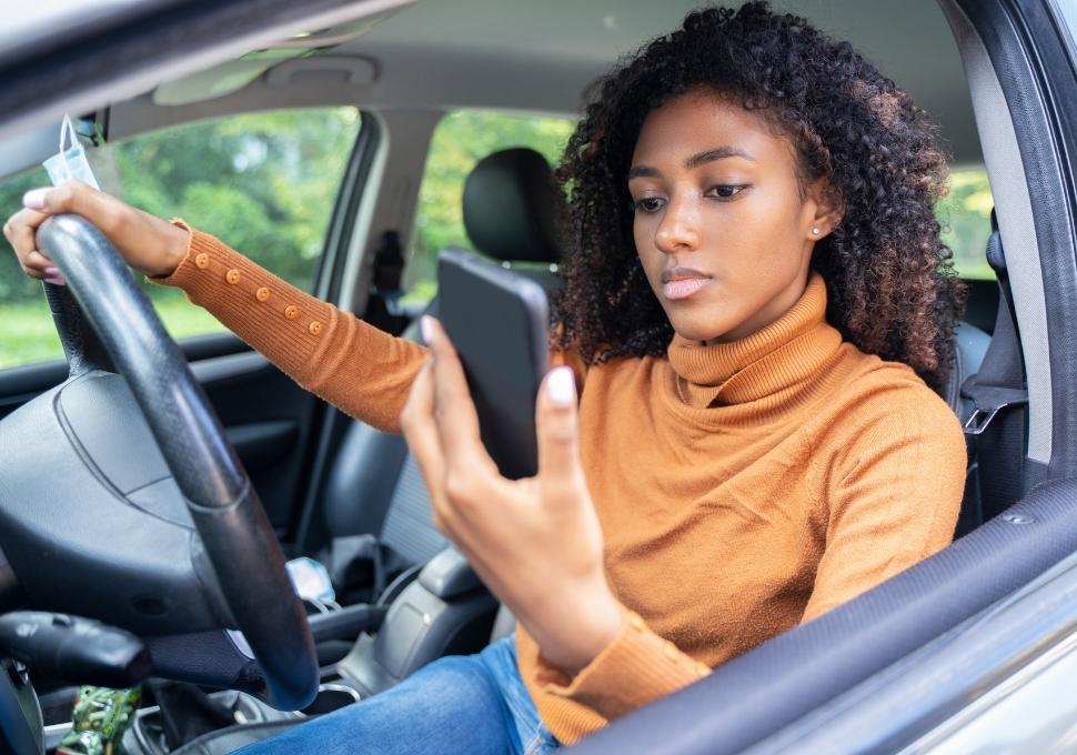woman driving while looking at her phone
