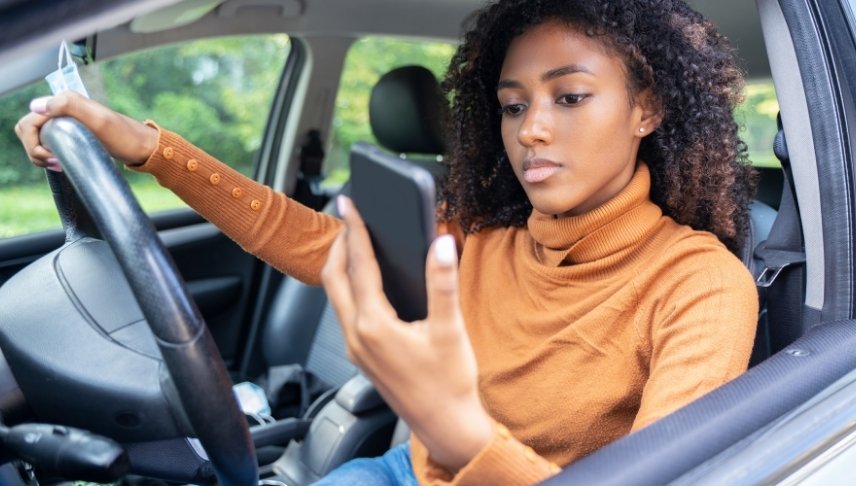 woman driving while browsing her phone